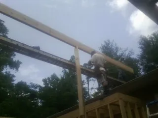 Carpenter setting a ridge beam over a new addition frame — Ice Dam Removal by Roofing Brothers in Falconer