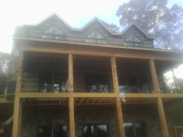 Dormers and porch framing on a large log home under construction — Roof Coating work by our crew in Falconer