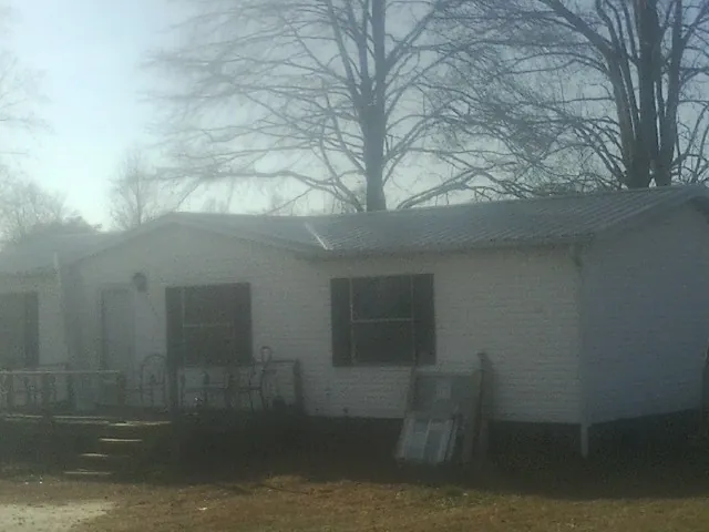 New metal roof on a white painted brick home on a foggy morning in Falconer