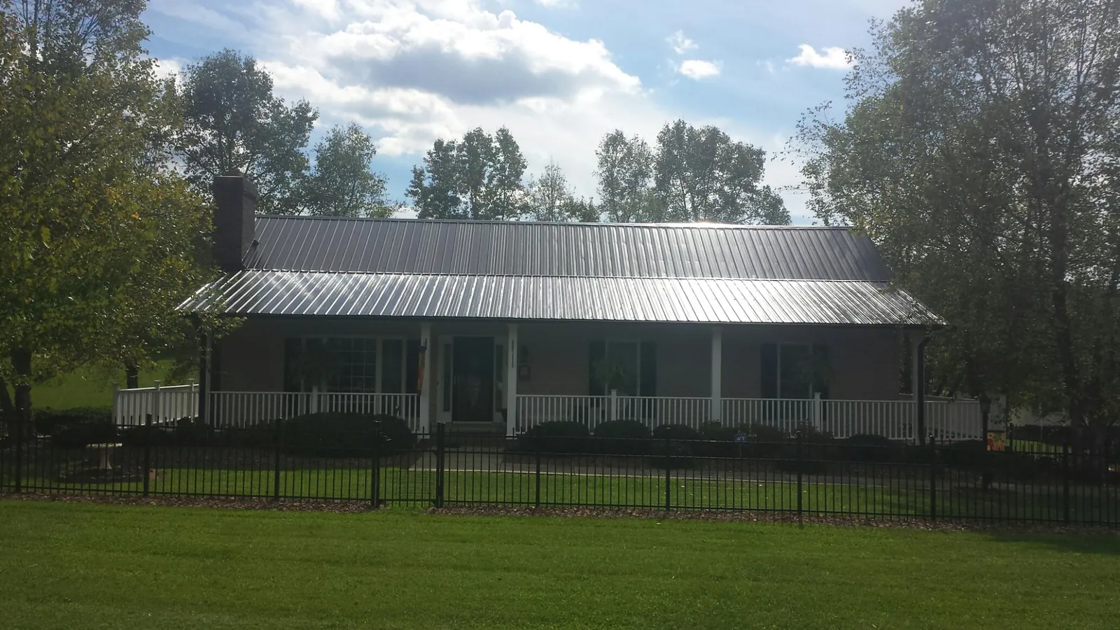 Gray metal roof on a brick ranch with a full width front porch — Gutter Guard Installation work by our crew in Falconer