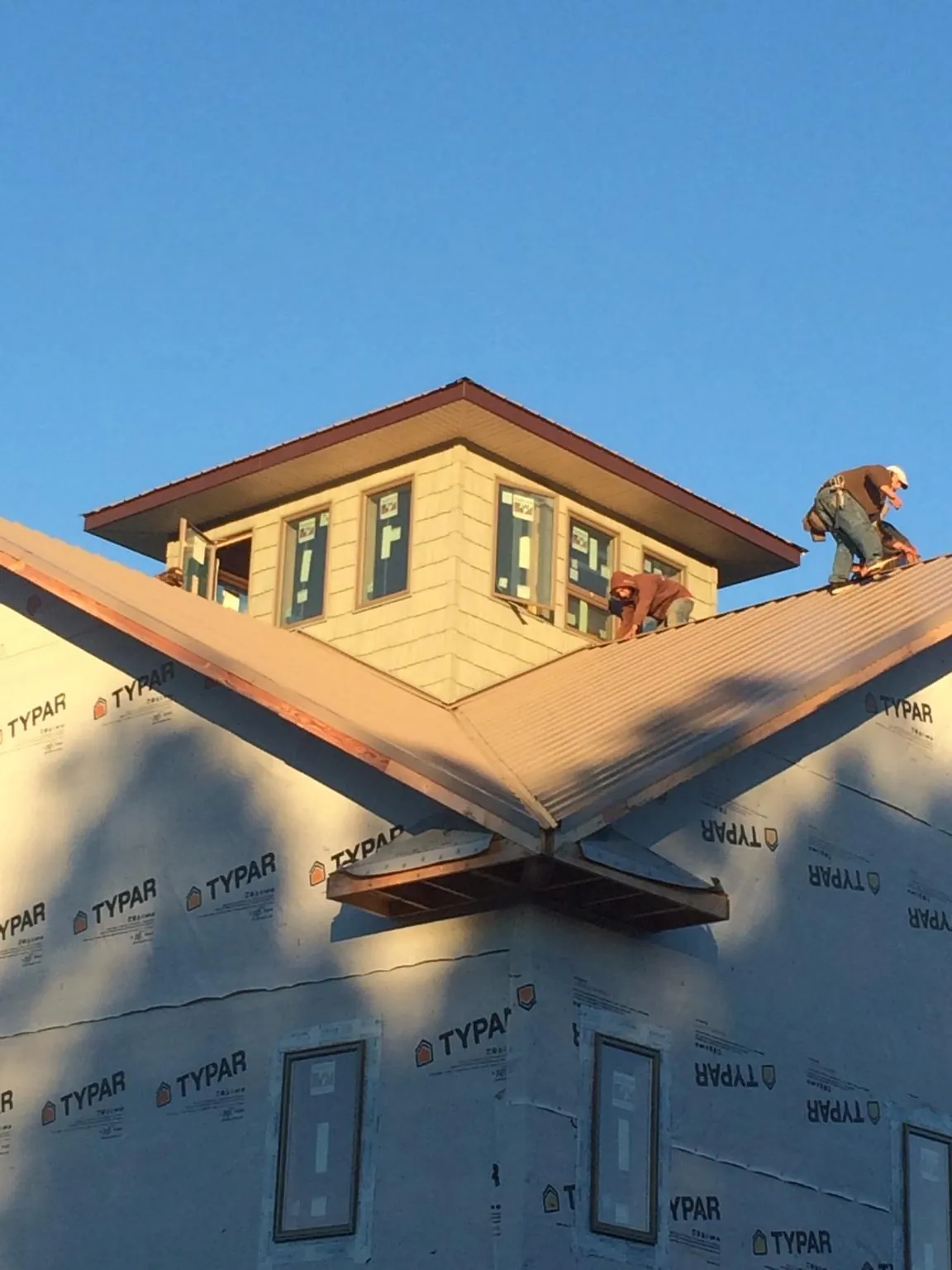 Roofers working around a rooftop cupola on a new metal roof at sunset — Roof Waterproofing in Falconer by Roofing Brothers